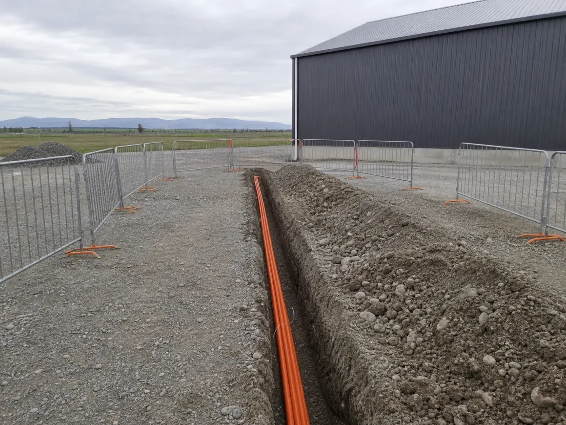 Orange electrical ducting laid in a service trench across the Rolleston yard